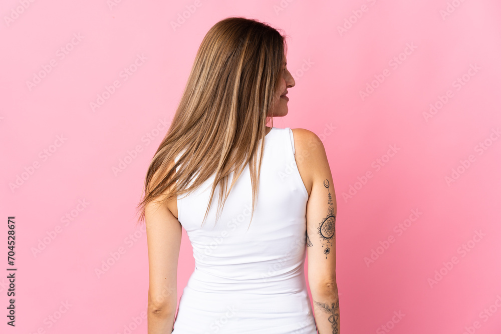 Young slovak woman isolated on pink background in back position and looking side Young slovak woman isolated on pink background in back position and looking side