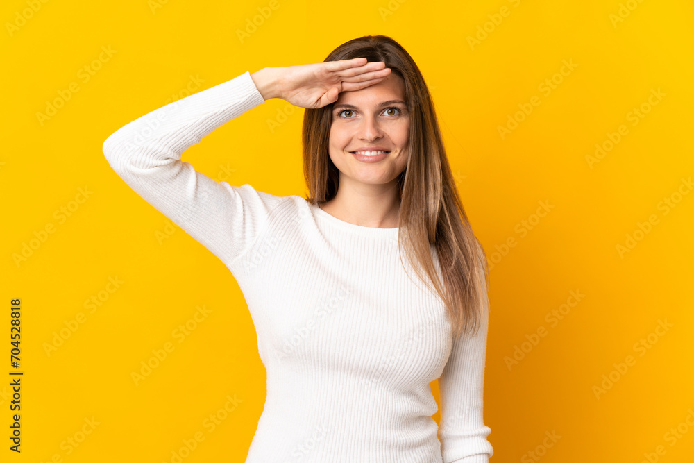 Young Slovak woman isolated on yellow background saluting with hand with happy expression Young Slovak woman isolated on yellow background saluting with hand with happy expression