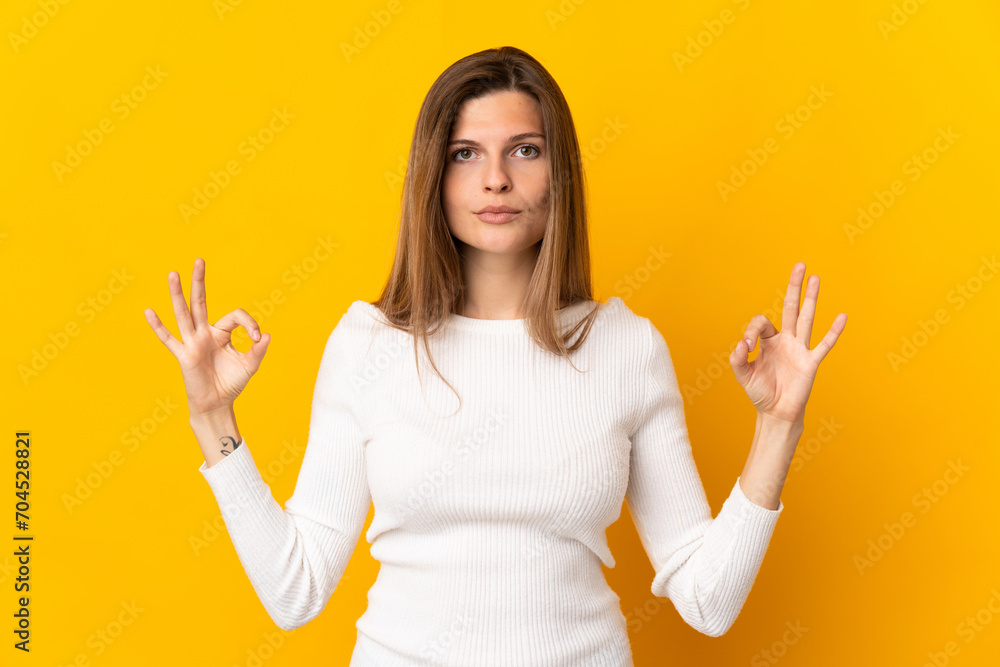 Young Slovak woman isolated on yellow background in zen pose Young Slovak woman isolated on yellow background in zen pose