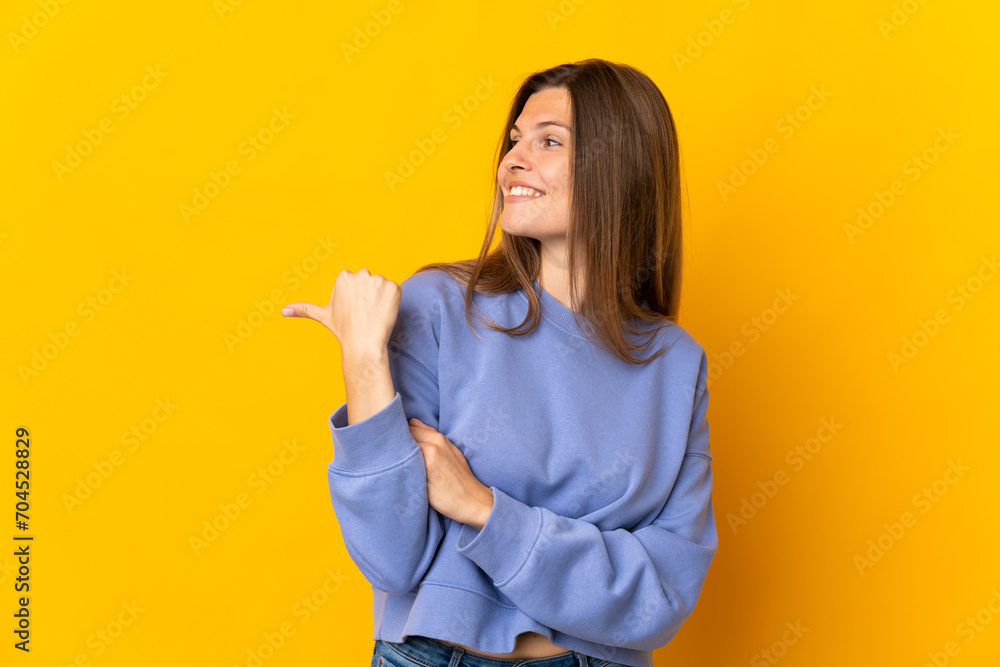 Young Slovak woman isolated on yellow background pointing to the side to present a product Young Slovak woman isolated on yellow background pointing to the side to present a product