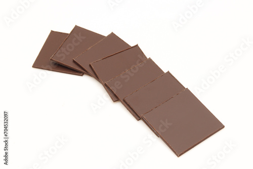 Stack of thin square pieces of chocolate isolated on white background.