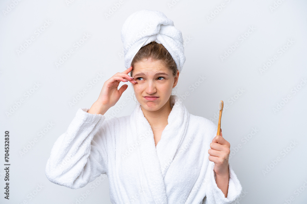 Teenager Russian girl brushing teeth isolated on white background having doubts and with confuse face expression Teenager Russian girl brushing teeth isolated on white background having doubts and with confuse face expression