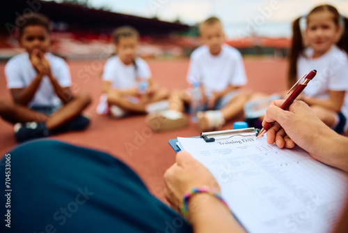 Close up of PE teacher takes notes during exercise class with kids. photo
