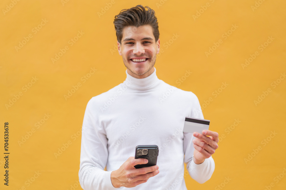 Young caucasian man at outdoors buying with the mobile with a credit card Young caucasian man at outdoors buying with the mobile with a credit card