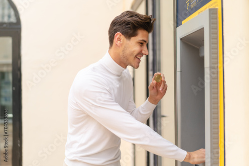 Young caucasian man at outdoors using an ATM © luismolinero