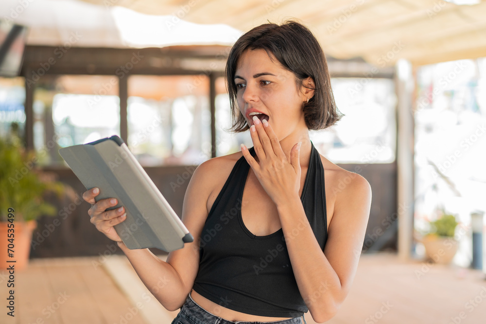 Young pretty Bulgarian woman holding a tablet at outdoors with surprise and shocked facial expression Young pretty Bulgarian woman holding a tablet at outdoors with surprise and shocked facial expression