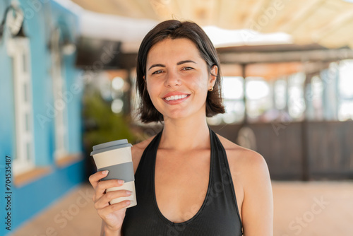 Young pretty Bulgarian woman at outdoors holding a take away coffee with happy expression © luismolinero