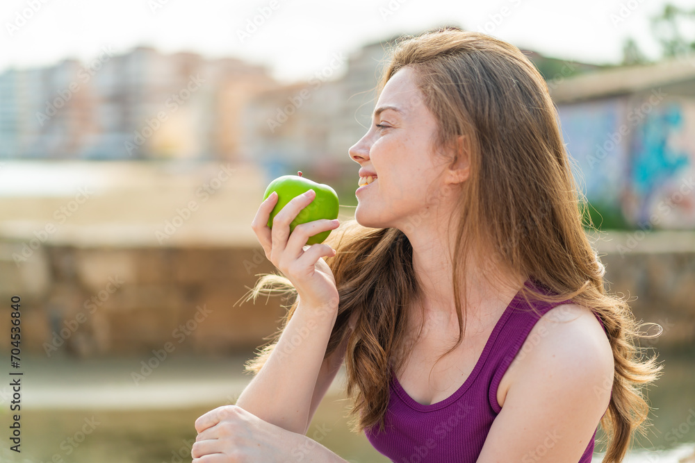 Young redhead woman at outdoors eating an apple Young redhead woman at outdoors eating an apple