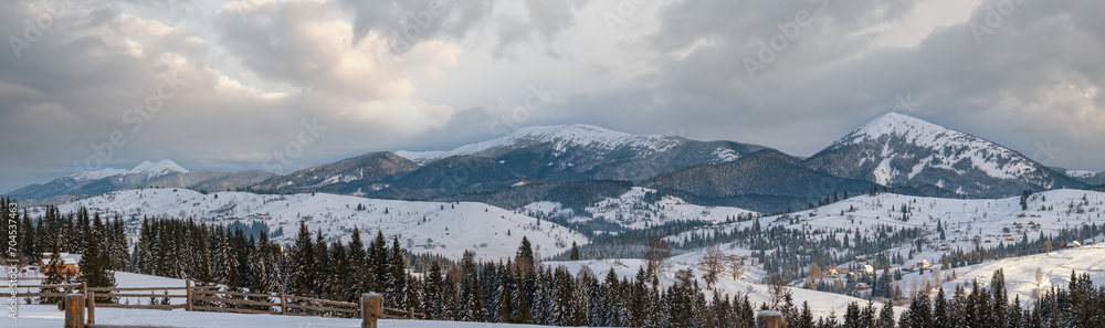 Small alpine village and winter snowy mountains in first sunrise sunlight around, Voronenko, Carpathian, Ukraine.