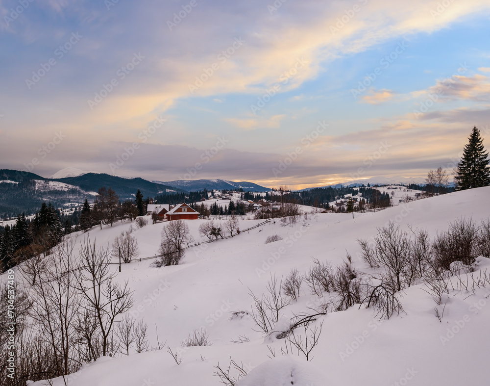 Small alpine village and winter snowy mountains in last sunset sunlight around, Voronenko, Carpathian, Ukraine.