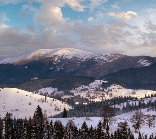 Small alpine village and winter snowy mountains in first sunrise sunlight around, Voronenko, Carpathian, Ukraine.