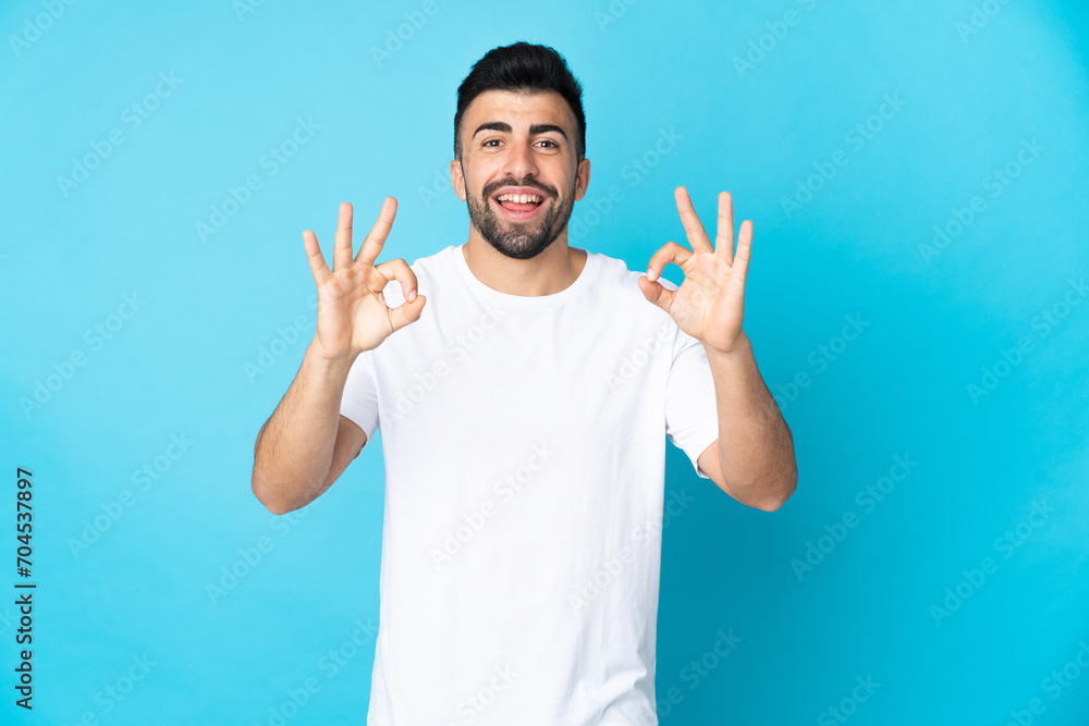 Naklejka premium Caucasian man over isolated blue background showing ok sign with two hands