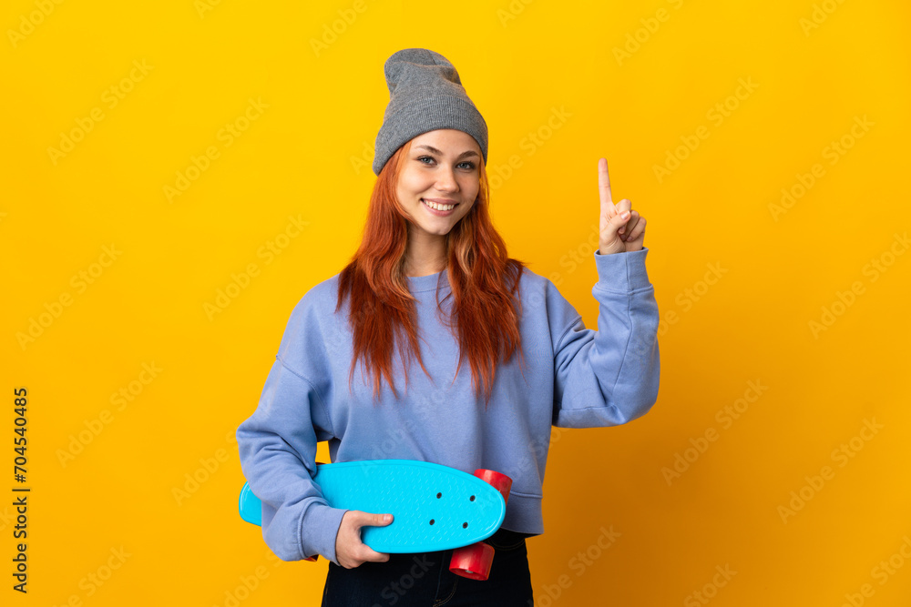 Teenager Russian skater girl isolated on yellow background showing and lifting a finger in sign of the best Teenager Russian skater girl isolated on yellow background showing and lifting a finger in sign of the best