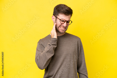 Young caucasian man isolated on yellow background with toothache