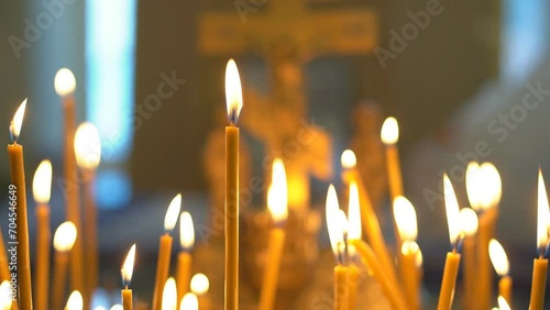Lighting wax candles inserted in sand burning in temple spreading light on blurred background. Worship traditions in Christian church close view photo