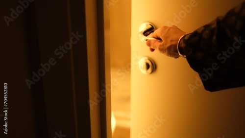 A man opens the door with the warm light on, close-up of his hands
