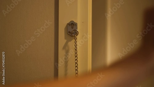 a man opens a door lock on a chain and leaves the house