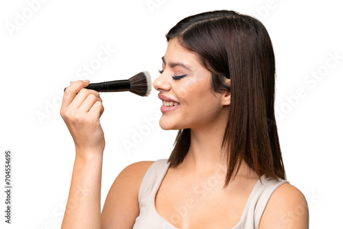 Young Russian woman with rainproof coat and umbrella over isolated chroma key background holding makeup brush and whit happy expression