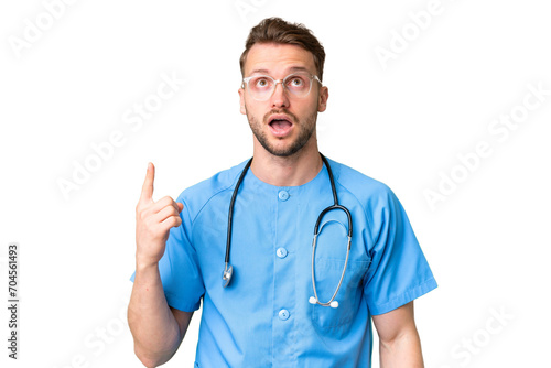 Young nurse man over isolated chroma key background pointing up and surprised