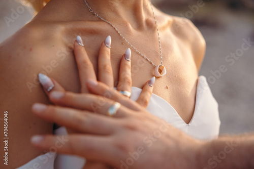 Wedding concept, couple touching their hands with wedding ring bands. Sea necklace. Loving married young couple.