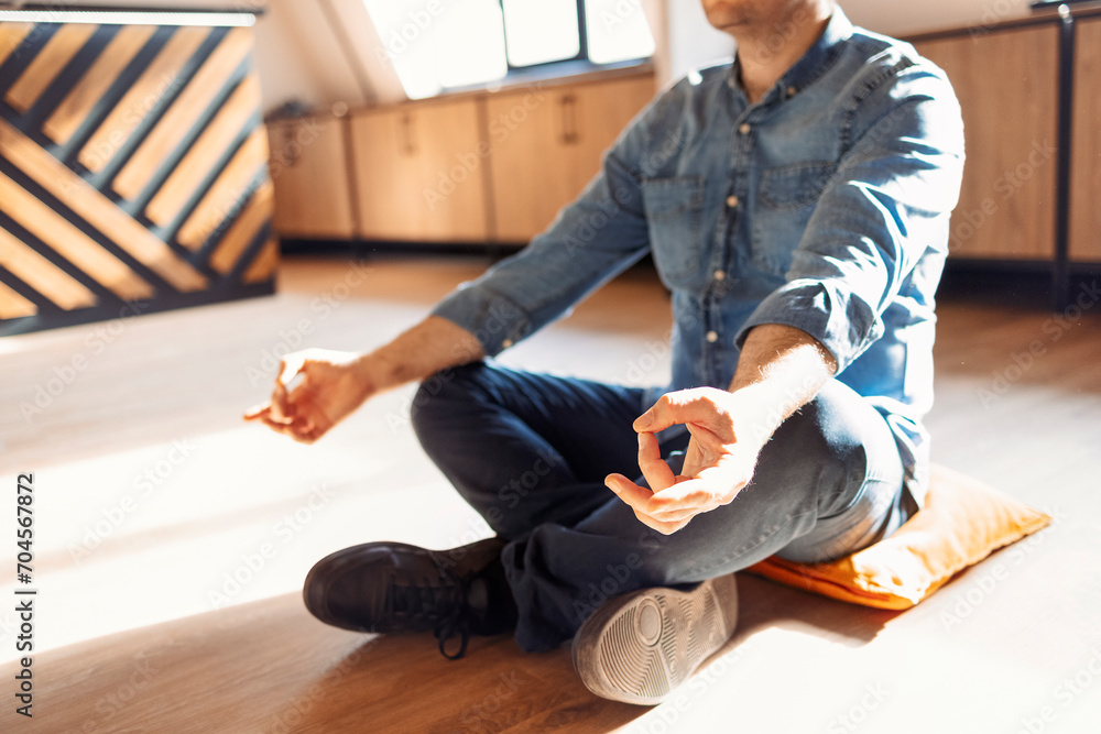 Fototapeta premium Handsome hispanic man wearing jeans casual shirt sitting on the floor at home relax, doing meditation gesture with fingers. Yoga concept