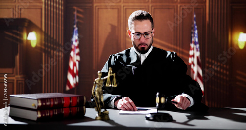 Male Judge Reading Documents While Sitting At Desk