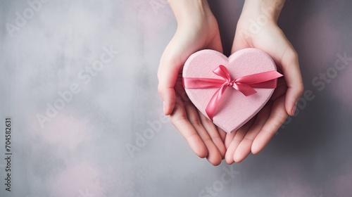First person top view photo of valentine s day decorations young woman s hands holding heart shaped giftbox with pink ribbon bow on isolated gray background  generative ai