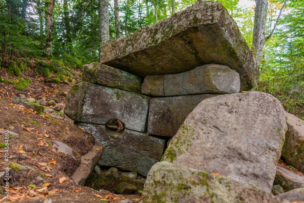 ancient dilapidated dolmen with a round hole in the wall and a stone roof in the mountains of the western caucasus (southern russia) on a sunny summer day ancient dilapidated dolmen with a round hole in the wall and a stone roof in the mountains of the western caucasus (southern russia) on a sunny summer day