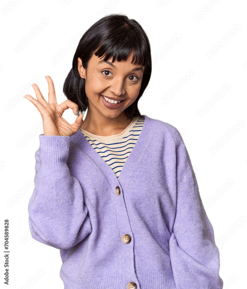 Young Hispanic woman with short black hair in studio winks an eye and holds an okay gesture with hand. Young Hispanic woman with short black hair in studio winks an eye and holds an okay gesture with hand.