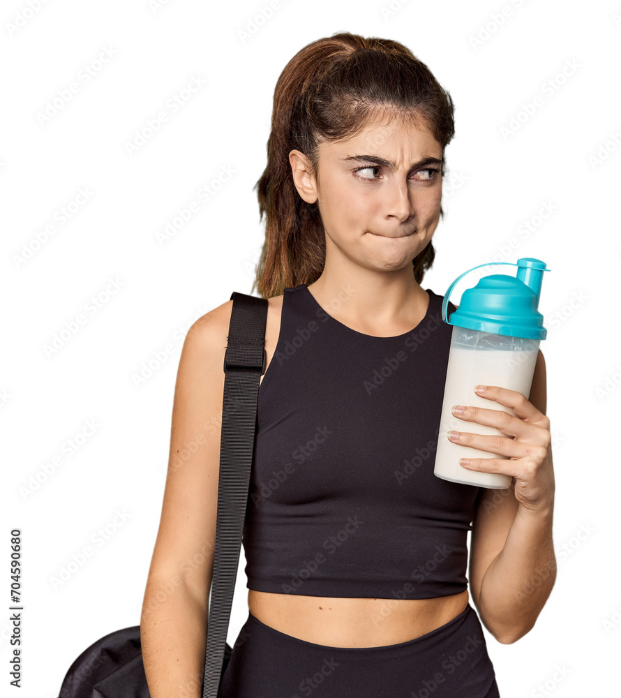 Athletic Caucasian woman holding protein shake confused, feels doubtful and unsure. Athletic Caucasian woman holding protein shake confused, feels doubtful and unsure.