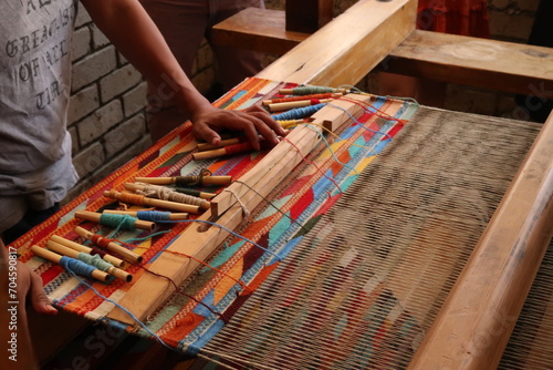 Man in a workshop standing next to a traditional loom, about to weave a colorful carpet, Oaxaca, Mexico photo