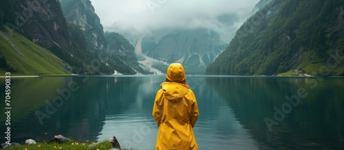 Adventurous girl explores a lakeside in a yellow raincoat, enjoying the scenic view on a cool day.