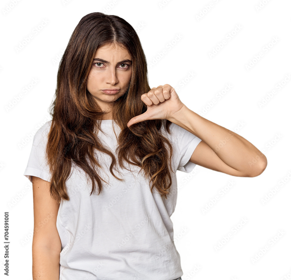 Young Caucasian woman in studio setting showing thumb down, disappointment concept. Young Caucasian woman in studio setting showing thumb down, disappointment concept.