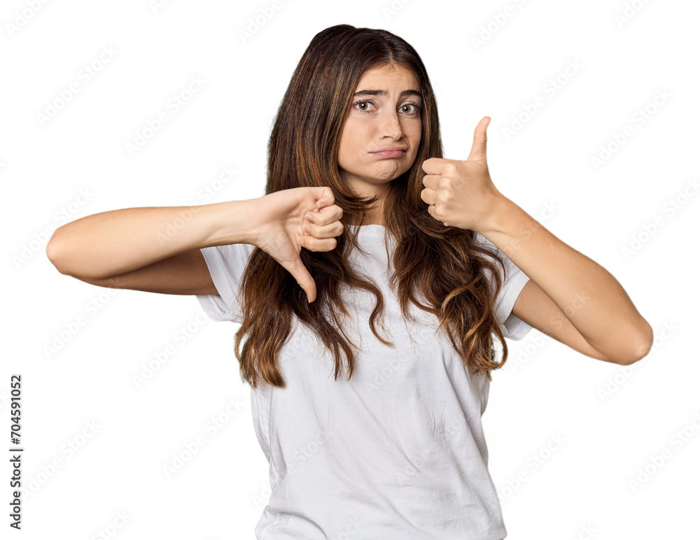 Fototapeta premium Young Caucasian woman in studio setting showing thumbs up and thumbs down, difficult choose concept