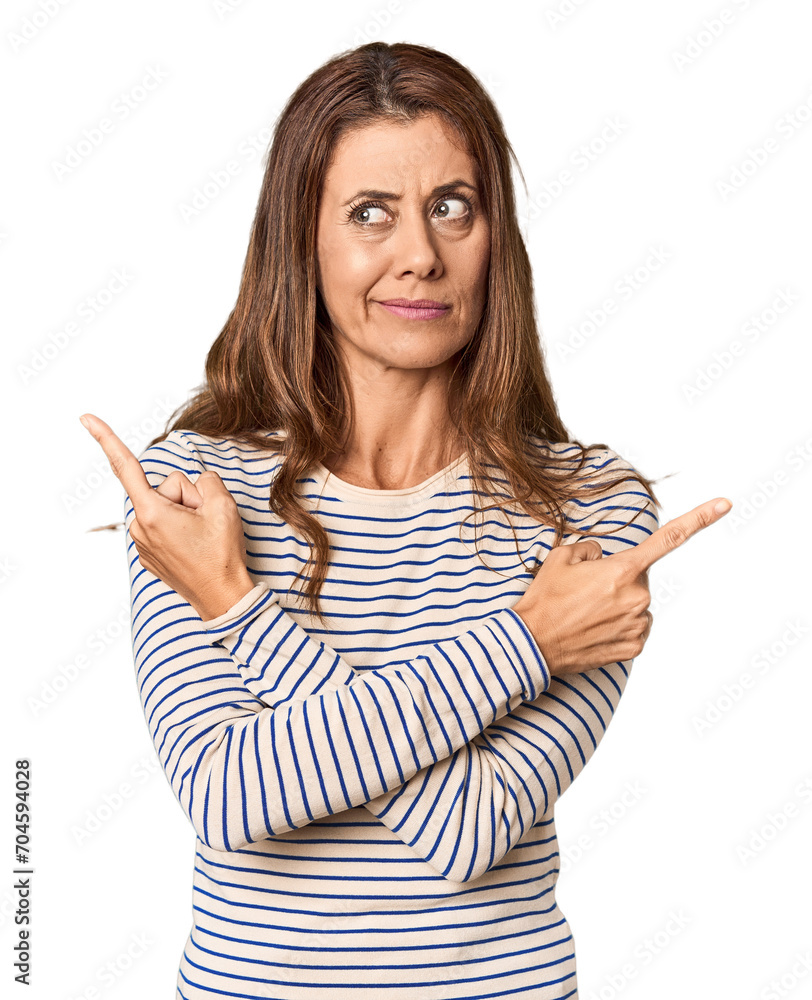 Middle-aged woman portrait in studio setting points sideways, is trying to choose between two options. Middle-aged woman portrait in studio setting points sideways, is trying to choose between two options.