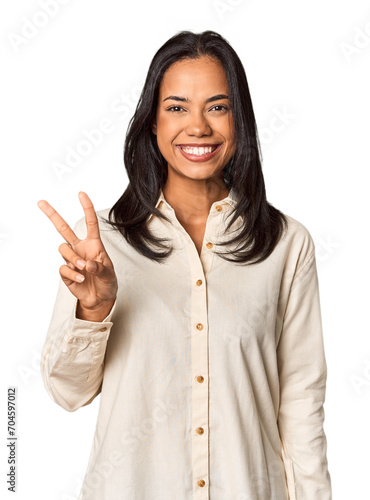 Young Filipina with long black hair in studio showing victory sign and smiling broadly.