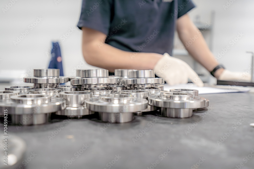 A worker inspects and sorts round parts with holes for assembling them into components and assemblies.