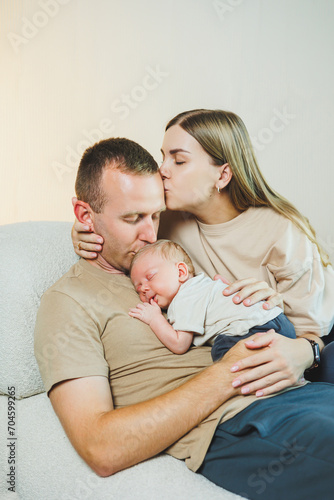 Happy mother and father hugging their newborn baby. Parents and a smiling child in their arms. A young family with a newborn baby.