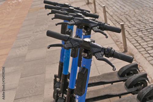 A number of electric scooters are parked on the street