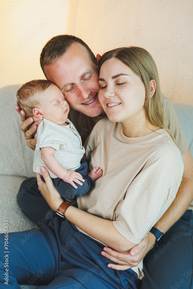 Happy mother and father hugging their newborn baby. Parents and a smiling child in their arms. A young family with a newborn baby. Happy mother and father hugging their newborn baby. Parents and a smiling child in their arms. A young family with a newborn baby.