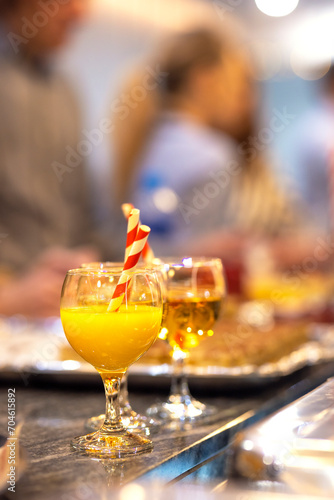 A glass cup with natural fresh orange juice at a children's party with a paper stream on a table, healthy citrus cocktail