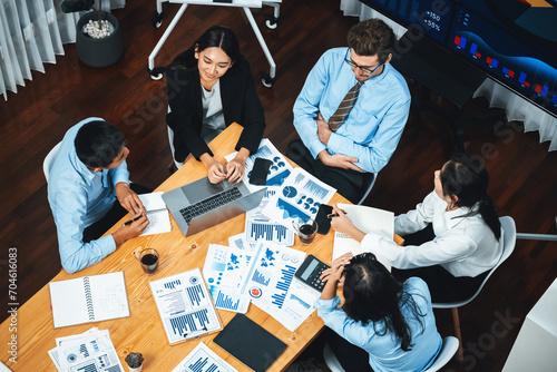 Wide top view of diverse group of business analyst team analyzing financial data report paper on meeting table. Chart and graph dashboard by business intelligence analysis. Meticulous