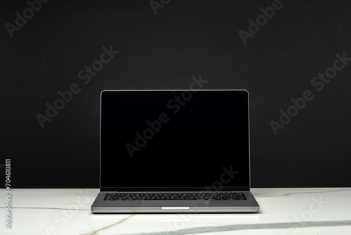 Open laptop with black screen against black background