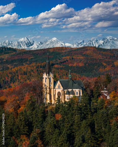 Levoca, Slovakia - Aerial view of Basilica of the Blessed Virgin Mary on a bright autumn day with the snowy summit of Marianska mountain of the High Tatras and blue sky with clouds at background photo