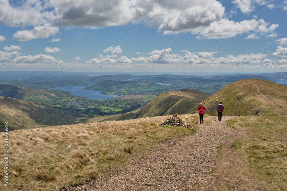 Obraz premium Windermere and Ambleside with hikers seen from the slopes of Farifield on the Fairfield Horseshoe, Lake District, UK