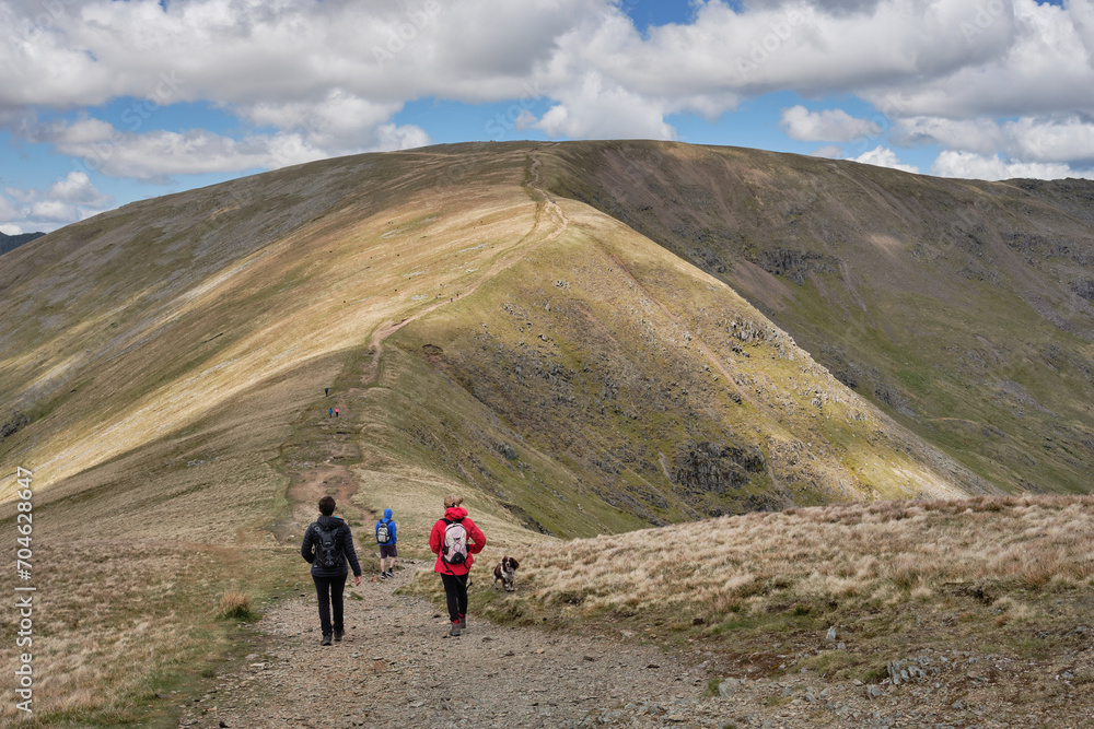 Hikers with dog descend Great Dodd on theri way up to the summit of Fairfield, on the Fairfield Horseshoe, Lake District, UK