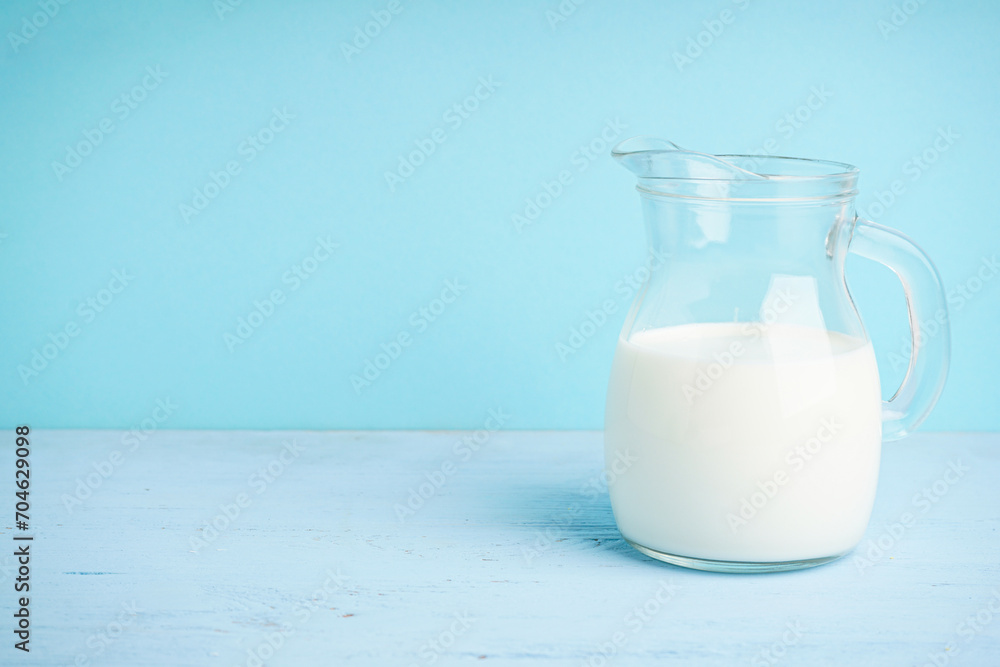 Jug with milk on a wooden light blue background, space for text. Jug with milk on a wooden light blue background, space for text.