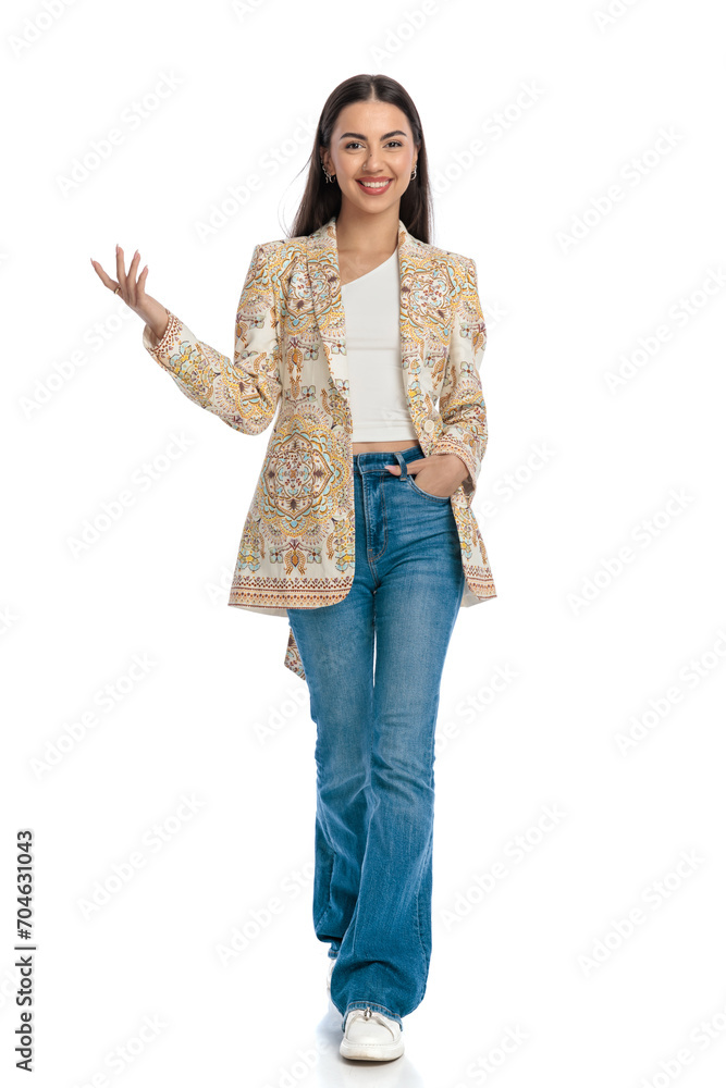 beautiful young woman showing to side, smiling and holding hands in pockets beautiful young woman showing to side, smiling and holding hands in pockets