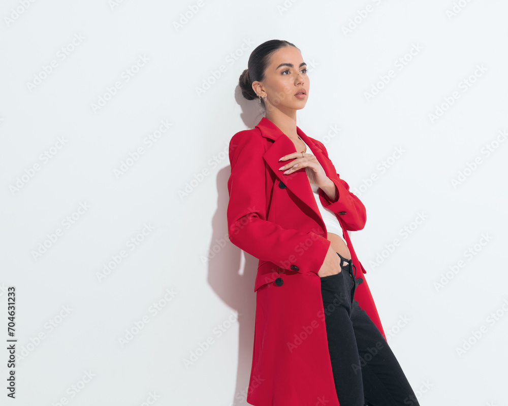 cool fashion woman in red coat holding hand in pocket and looking away cool fashion woman in red coat holding hand in pocket and looking away