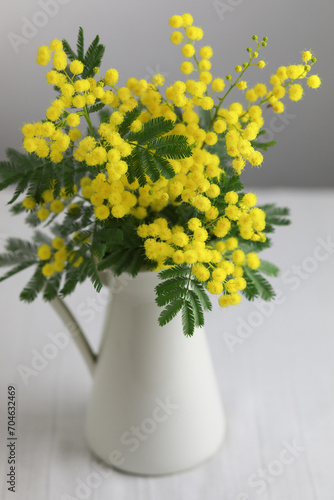 Vase with mimosa flowers branch on the table
